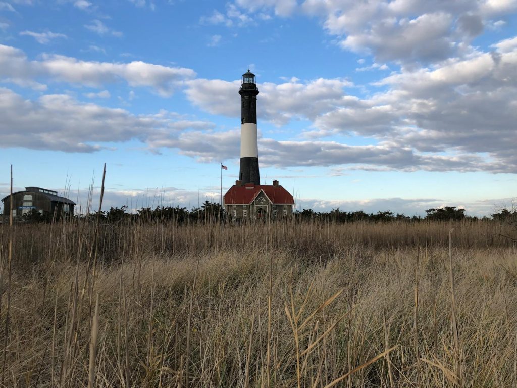 Beautiful view of Fire Island Lighthouse with a golden sky and field. Iconic New York landmark.