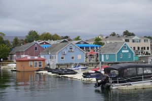 Scenic view of a marina with colorful boathouses and boats on a cloudy day.
