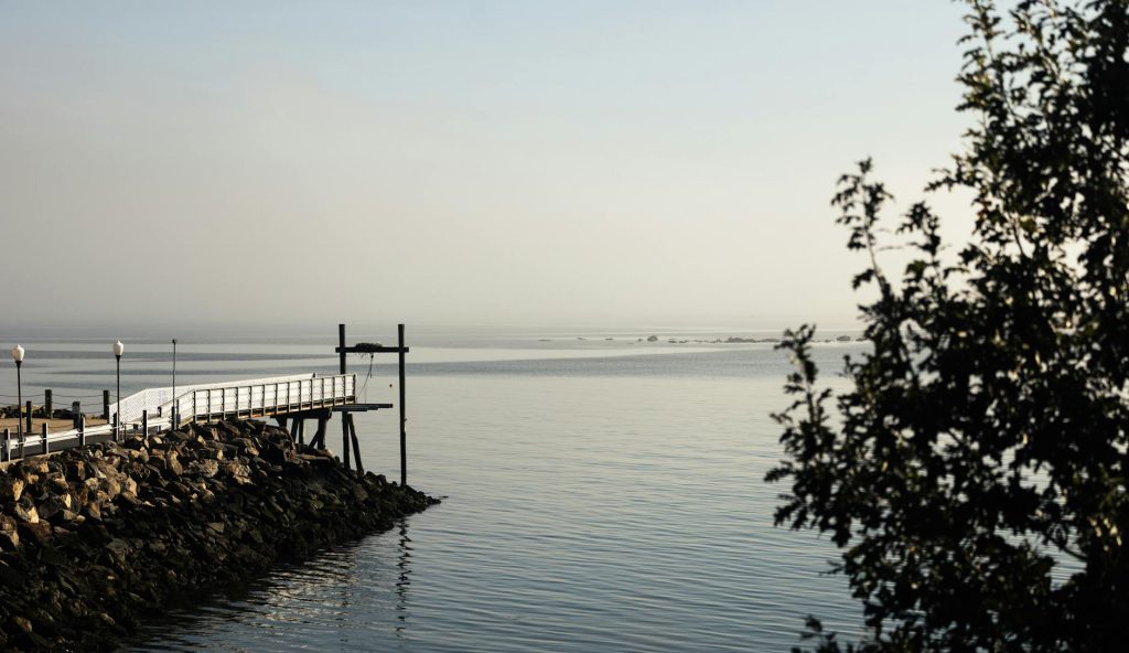 Peaceful coastal view of a rocky pier extending into calm waters at dawn.