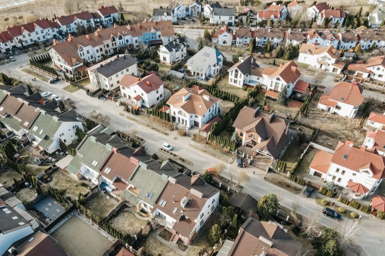 Drone view of a suburban residential area with houses and streets in daylight.