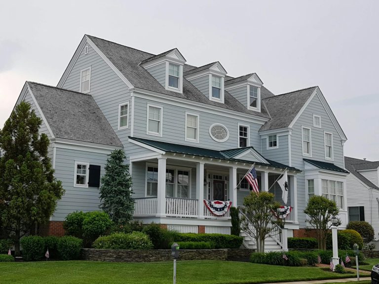 Elegant colonial-style house in Cape May, NJ with manicured lawn and American flags.