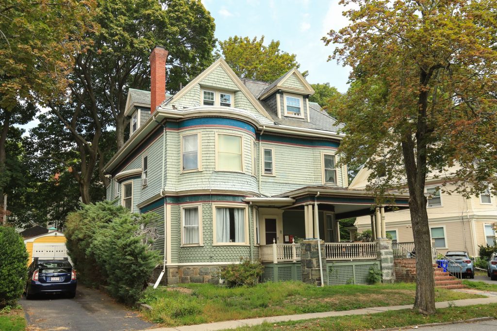 A charming Victorian house with a porch and surrounding trees, perfect for suburban living concepts.