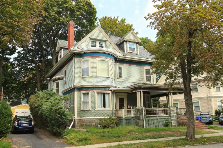 A charming Victorian house with a porch and surrounding trees, perfect for suburban living concepts.