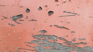Close-up of a red wall with peeling paint revealing the surface beneath. Ideal for backgrounds.